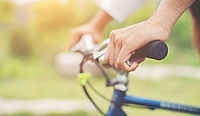 Close Up on biking man hands on the blurred nature sunrise backg
