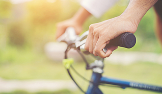 Close Up on biking man hands on the blurred nature sunrise backg