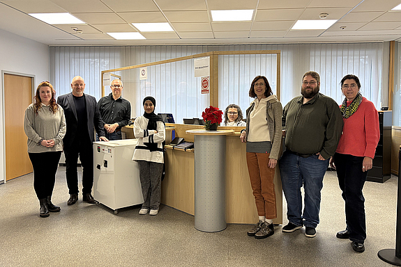 Sieben Personen stehen vor der neuen Infotheke im Neuen Rathaus