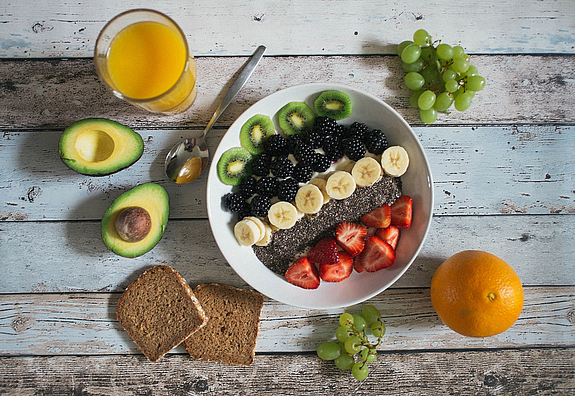 Aufgeschnittene Avocado, Orangensaft, Körnerbrot, Bowl mit Obst