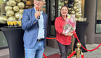 Der Oberbürgermeister steht mit Mikrofon in der Hand neben der Inhaberin auf einem roten Teppich