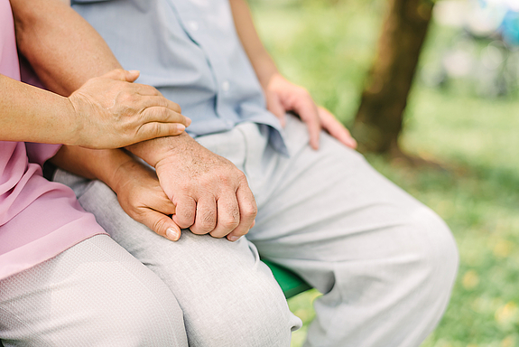 senior couple holding hands while sitting together