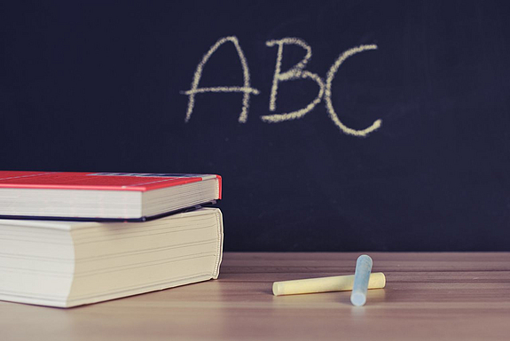 Bücher vor einer Tafel auf der ABC steht