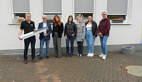 Beteiligte der Stadtverwaltung und der Geschäftsführer der ausführenden Firma stehen vor den Fenstern des Schulgebäudes an denen die Rollos zu sehen sind