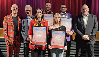 Geehrte und Verwaltung stehen vor der Bühne der Kulturhalle