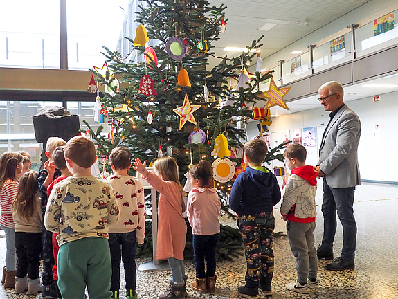 Kinder und Oberbürgermeister stehen vor dem geschmückten Tannenbaum.