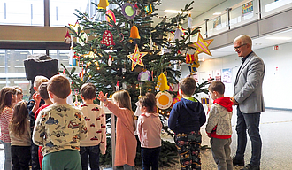Kinder und Oberbürgermeister stehen vor dem geschmückten Tannenbaum.
