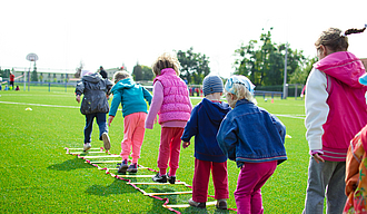Kinder hüpfen über auf dem Boden liegende Reifen auf einer Wiese