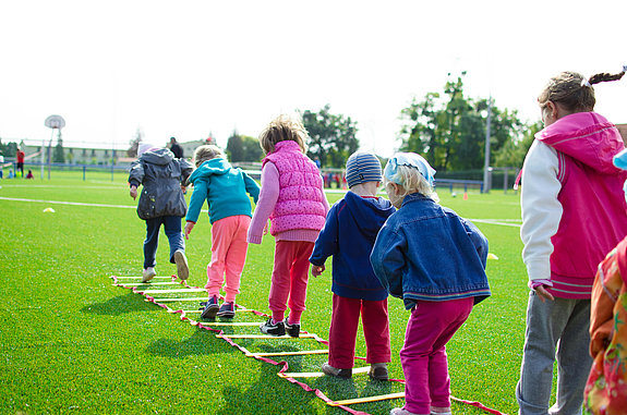Kinder hüpfen über auf dem Boden liegende Reifen auf einer Wiese