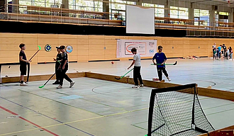 Vier Jungen mit Hockeyschlägern auf dem Kleinfeld in der Halle 