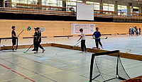 Vier Jungen mit Hockeyschlägern auf dem Kleinfeld in der Halle 