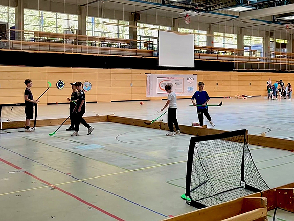 Vier Jungen mit Hockeyschlägern auf dem Kleinfeld in der Halle 